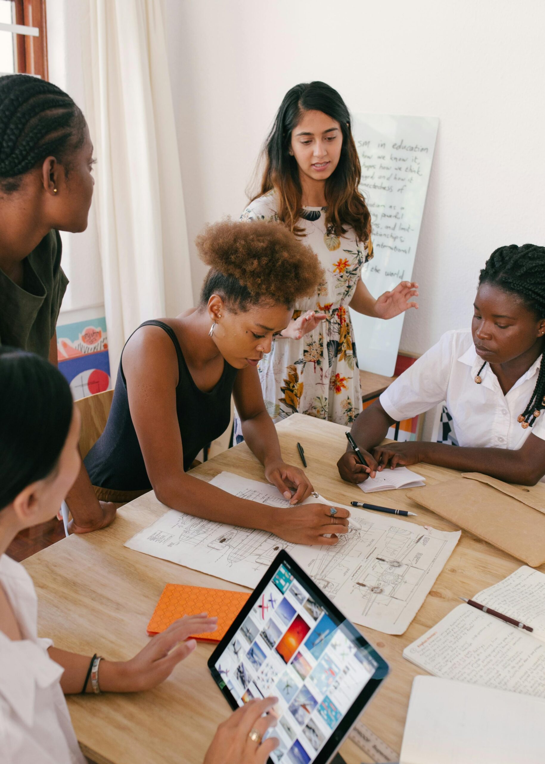 Group of women collaborating on a creative project in a modern office environment.